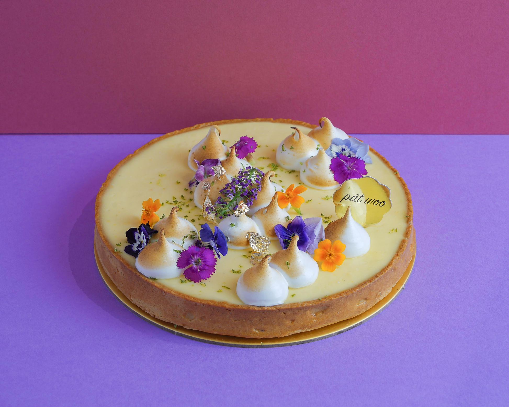 Smooth lemon curd sitting a top a buttery tart crust with edible flowers sprinkled on top.